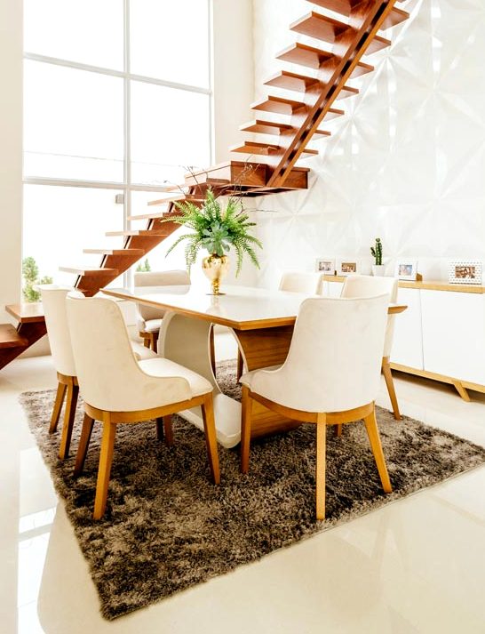 A breakfast room with a dining table, pale chairs and tall windows