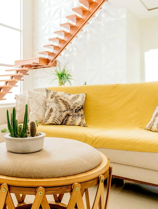A sitting corner with a yellow sofa, a cactus and a cane table